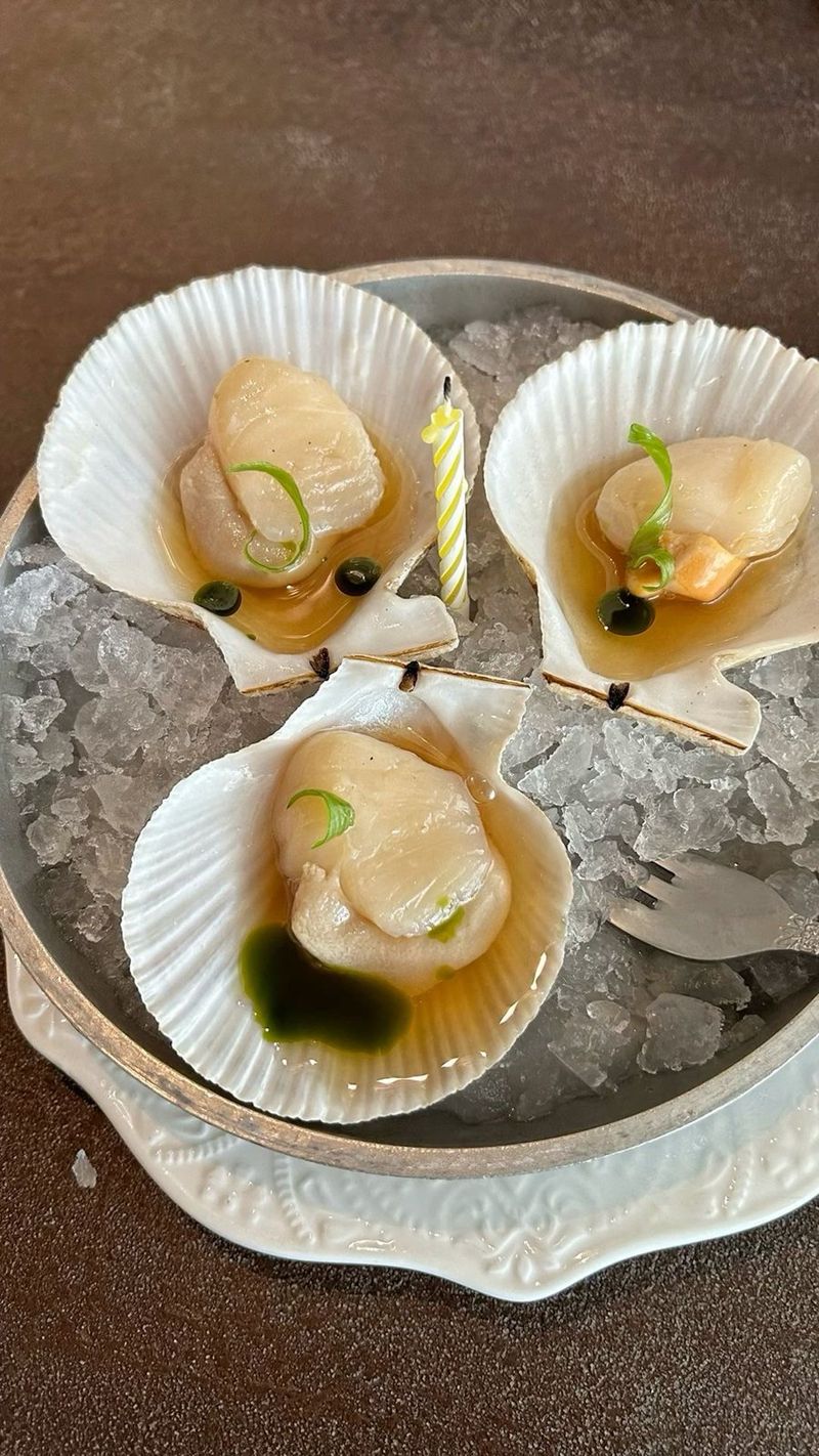 Three scallops served in their shells on crushed ice