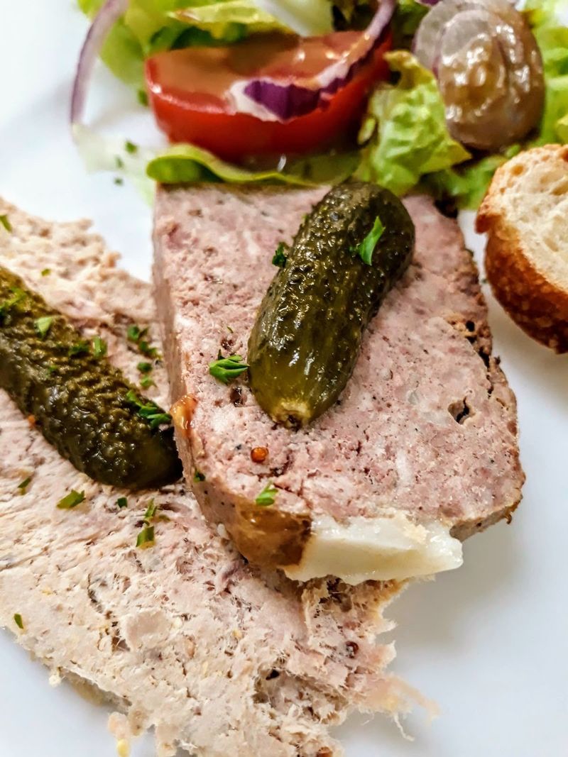 Slices of country terrine with cornichons, salad and bread