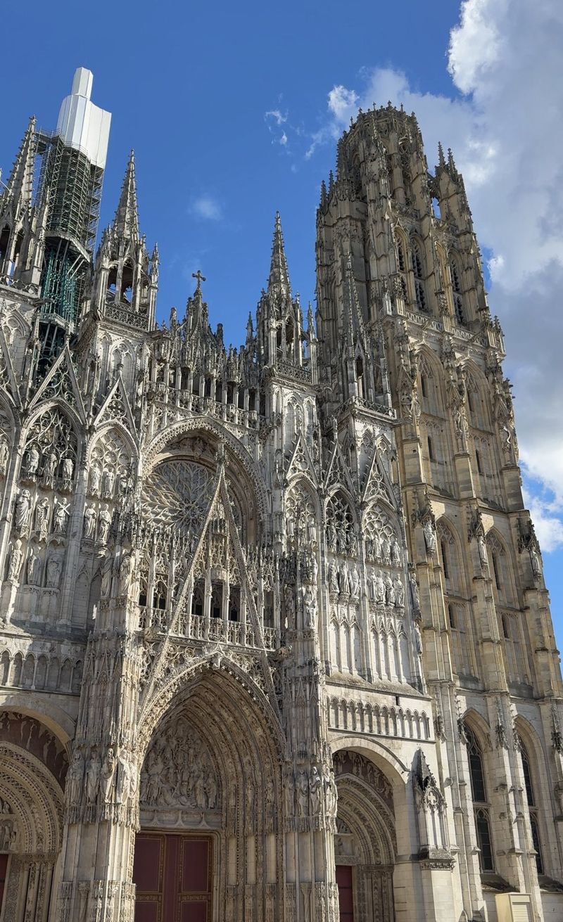 The ornate Gothic façade and towers of Rouen Cathedral against a blue sky