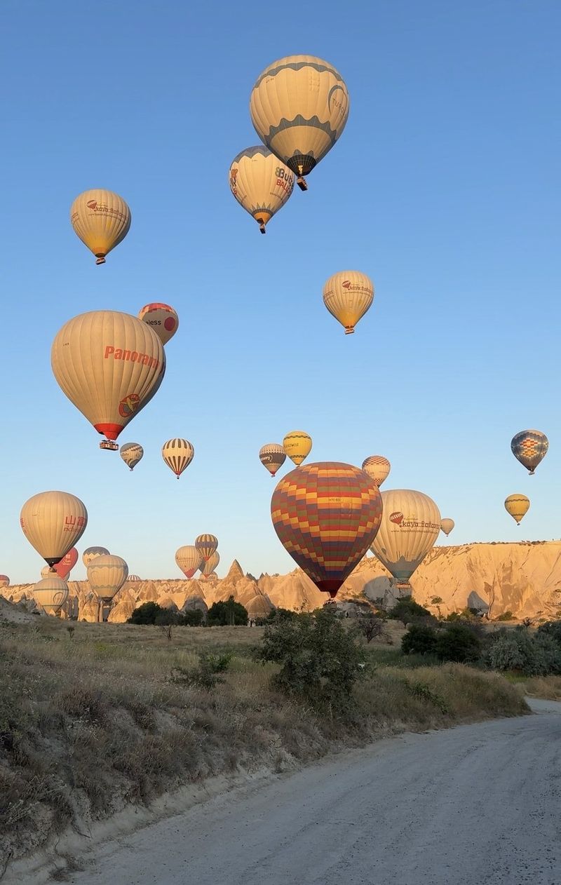 Dozens of hot-air balloons in a clear blue morning sky above the valleys of Cappadocia
